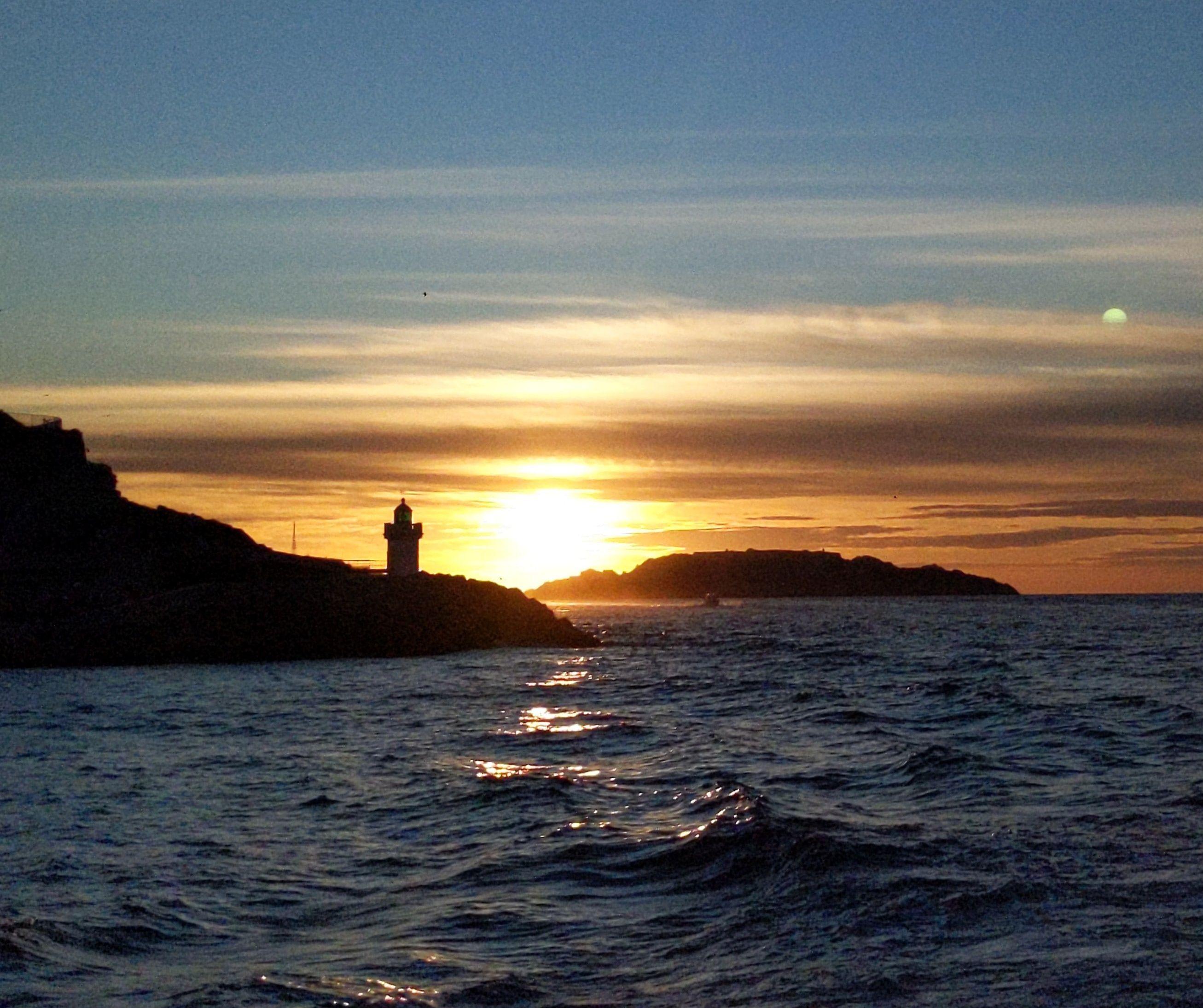Sunset over the Mediterranean. A lighthouse stands in the middle of the photo.
